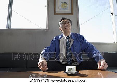 Stock Photo - Mature man sitting in sofa. Fotosearch