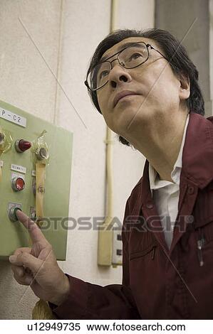 Stock Photography - Senior worker pressing button. Fotosearch