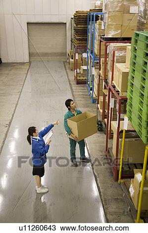 Stock Image - Two people working in warehouse. Fotosearch