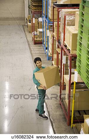 Young man carrying box in warehouse View Large Photo Image Picture - Young man carrying box in warehouse. Fotosearch