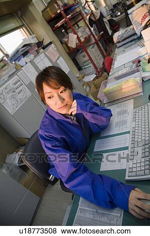 Stock Photo - Young woman sitting in office. Fotosearch