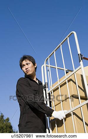Stock Image - Young worker carrying boxes. Fotosearch