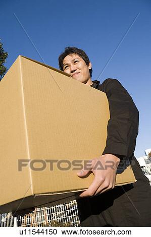 Stock Image - Young worker holding carton box. Fotosearch