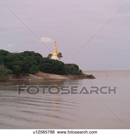 Stock Photo - Golden tower of Temple along shoreline. Fotosearch