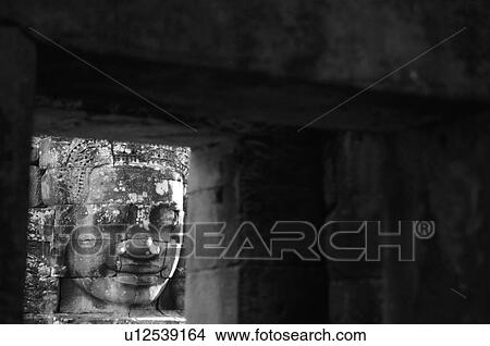 Picture - Stone carving of a face on wall at Khmer Kingdom palace ruins. Fotosearch