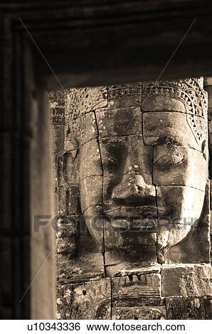 Stock Photograph - Stone carving of a face on wall at Khmer Kingdom palace ruins. Fotosearch