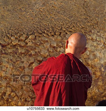 Stock Image - Monk putting gold leaf gilding on Golden Rock Shrine. Fotosearch