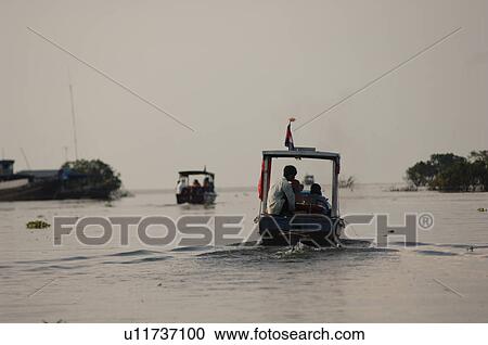 Stock Image - People riding in boats on waterway in Cambodia. Fotosearch