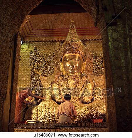 Stock Image - Pilgrims at a Buddhist temple in Mandalay. Fotosearch