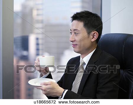 Businessman holding coffee standing by window, smiling View Large Photo Image Stock Image - Businessman holding coffee standing by window, smiling. Fotosearch