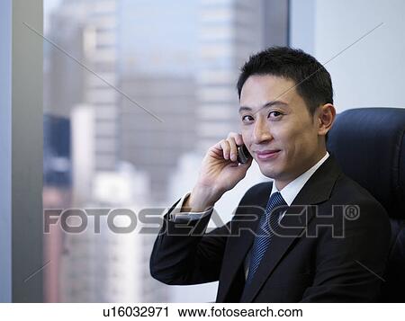 Stock Image - Businessman using mobile phone, smiling. Fotosearch