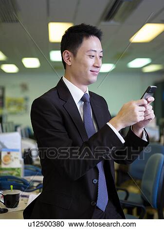 Businessman using mobile phone, text messaging View Large Photo Image Stock Image - Businessman using mobile phone, text messaging. Fotosearch