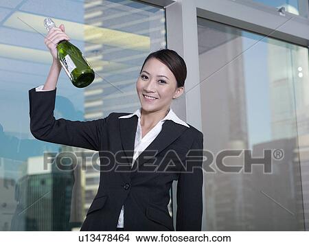 Businesswoman holding bottle of champagne View Large Photo Image Picture - Businesswoman holding bottle of champagne. Fotosearch