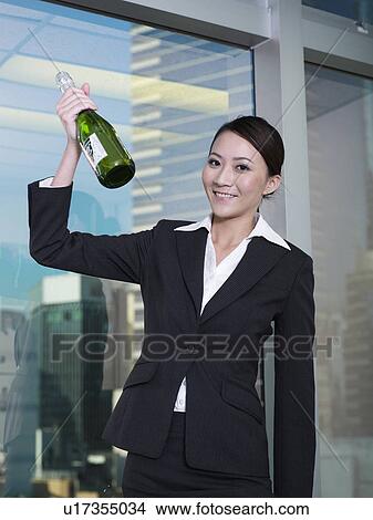 Picture - Businesswoman holding bottle of champagne. Fotosearch