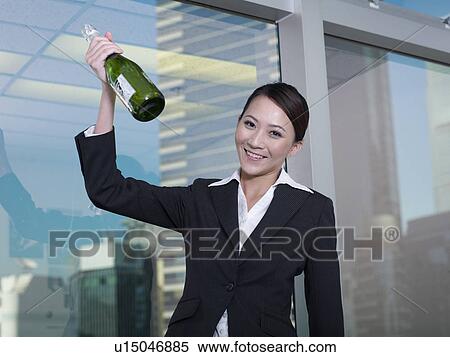 Stock Photography - Businesswoman holding bottle of champagne. Fotosearch