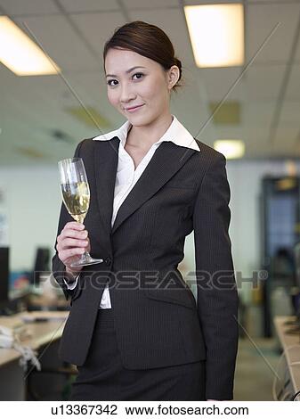 Stock Image - Businesswoman holding champagne glass, smiling. Fotosearch