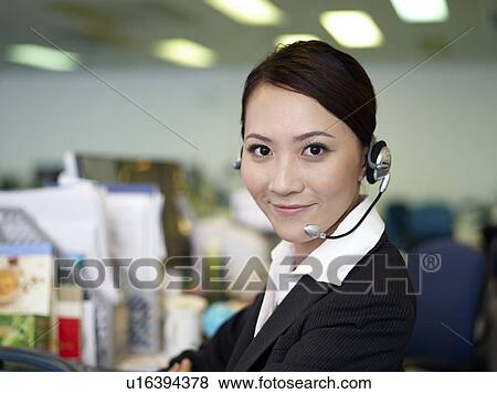 Stock Photo - Businesswoman wearing headset in office, smiling. Fotosearch