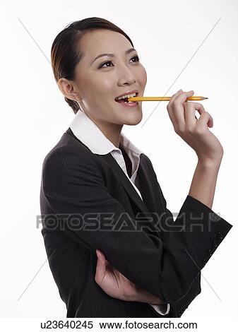 Stock Photography - Businesswoman biting pencil, close-up, portrait. Fotosearch