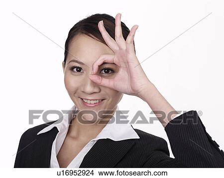 Picture - Businesswoman gesturing ok sign with fingers over eye. Fotosearch
