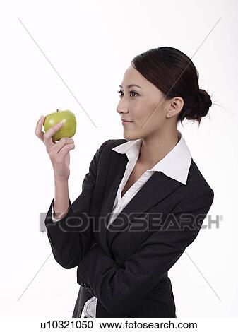 Businesswoman holding apple, smiling View Large Photo Image Stock Image - Businesswoman holding apple, smiling. Fotosearch