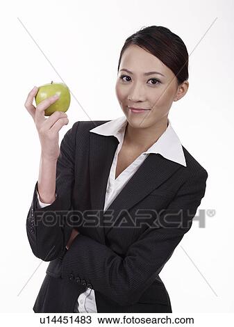 Businesswoman holding apple, smiling View Large Photo Image Stock Image - Businesswoman holding apple, smiling. Fotosearch