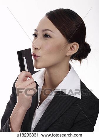 Stock Image - Businesswoman holding credit card, studio shot. Fotosearch