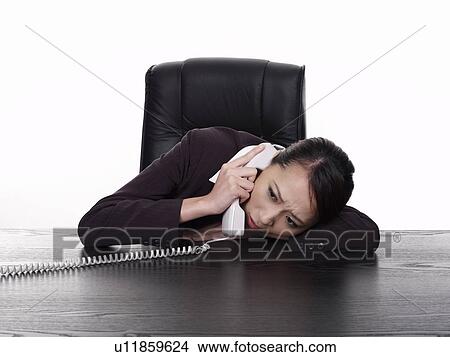 Businesswoman lying down on desk, using telephone View Large Photo Image Picture - Businesswoman lying down on desk, using telephone. Fotosearch