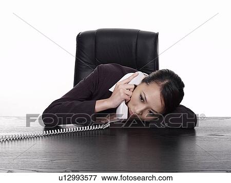 Stock Photo - Businesswoman lying down on desk, using telephone. Fotosearch