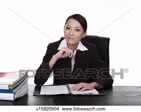 Picture - Businesswoman sitting at desk, working. Fotosearch