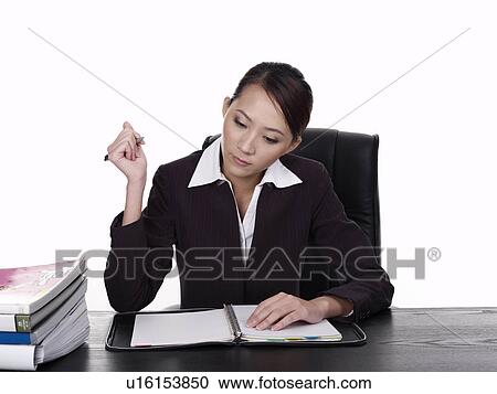 Businesswoman sitting at desk, working View Large Photo Image Stock Image - Businesswoman sitting at desk, working. Fotosearch
