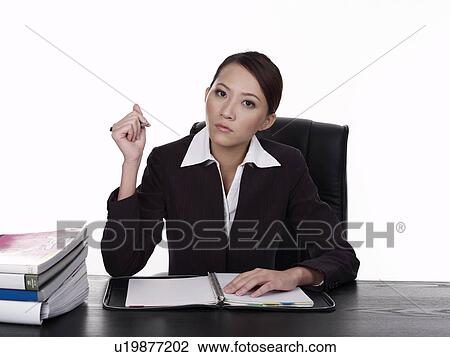 Businesswoman sitting at desk, working View Large Photo Image Stock Image - Businesswoman sitting at desk, working. Fotosearch