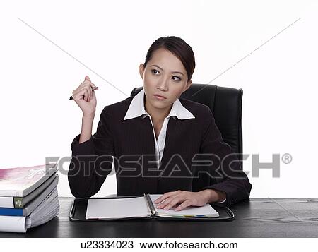 Stock Image - Businesswoman sitting at desk, working. Fotosearch
