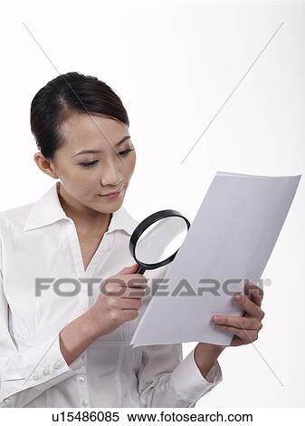 Stock Photography - Businesswoman using a magnifying glass to read. Fotosearch