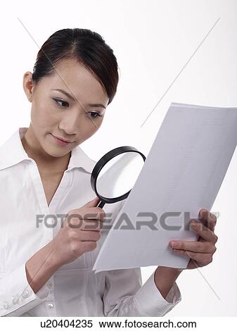 Stock Photography - Businesswoman using a magnifying glass to read. Fotosearch