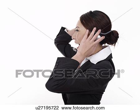 Stock Image - Businesswoman wearing telephone headset, screaming, close-up. Fotosearch