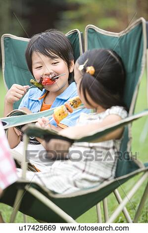 Stock Photo - Boy and girl biting on kebabs, differential focus. Fotosearch