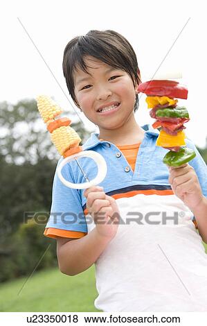 Stock Photo - Boy holding kebabs, smiling, looking at camera. Fotosearch