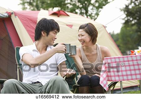 Stock Image - Couple toasting in front of tent. Fotosearch