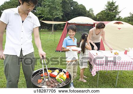 Stock Photography - Families Having BBQ on Grass Field. Fotosearch
