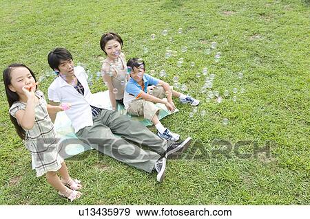 Family in field, girl blowing bubbles View Large Photo Image Stock Photo - Family in field, girl blowing bubbles. Fotosearch