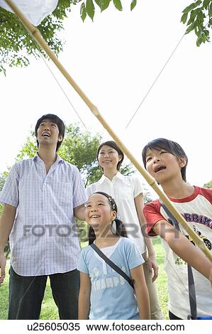 Stock Photography - Family of four standing, boy holding butterfly net. Fotosearch