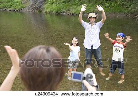Picture - Father, son and daughter waving hands to camera. Fotosearch
