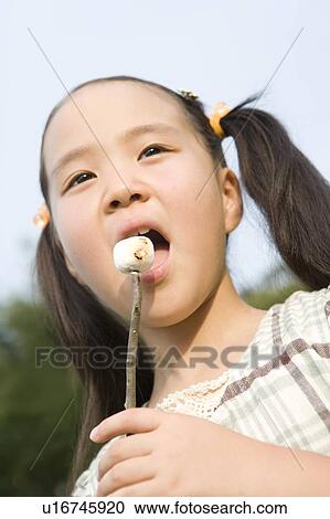 Stock Image - Girl Eating Roasted Marshmallow. Fotosearch