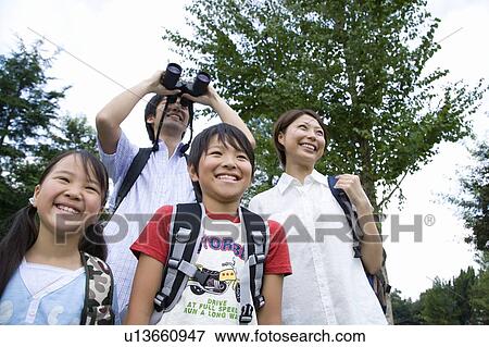 Stock Photo - Happy family in field, father looking through binoculars. Fotosearch