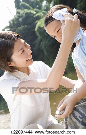 Mother wiping daughter's forehead with towel View Large Photo Image Picture - Mother wiping daughter's forehead with towel. Fotosearch