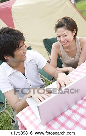 Stock Photograph - Young Couple Using Laptop in Outside. Fotosearch