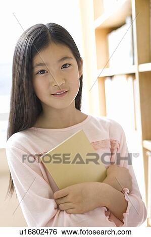 Stock Photograph - Elementary Girl Holding a Book. Fotosearch