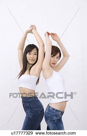 Two young women, bock to back, smiling, front view View Large Photo Image Stock Photo - Two young women, bock to back, smiling, front view. Fotosearch