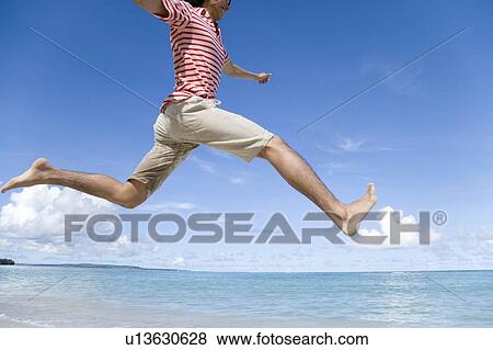 Stock Photo - Man jumping on beach, Saipan, USA . Fotosearch