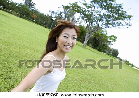 Stock Image - Portrait of a young woman on lawn, smiling, Saipan, USA . Fotosearch